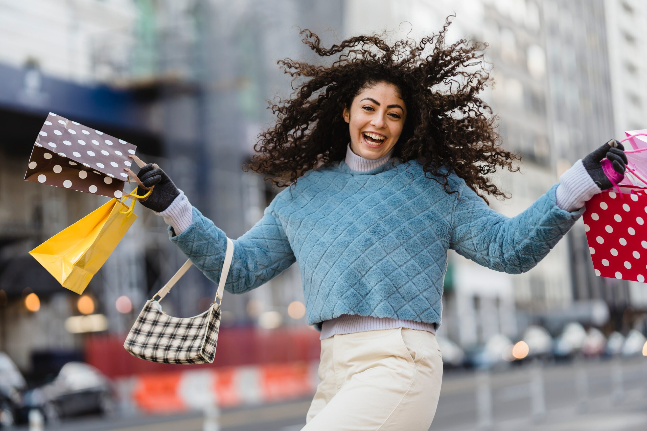 Woman smiling while holding her purse and shopping bags