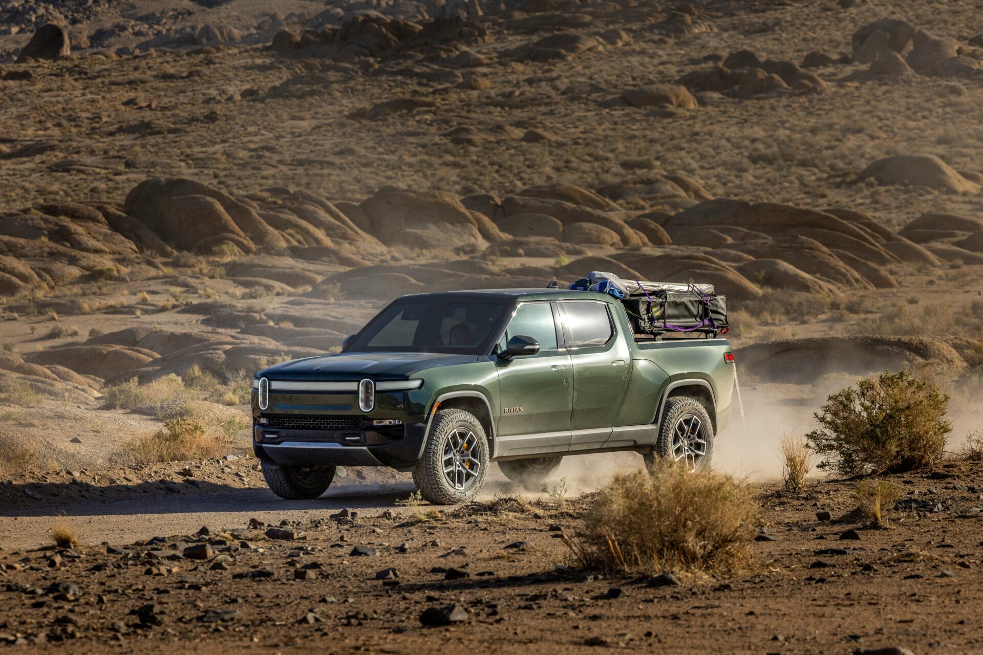 Green Rivian electric truck on a dirt road