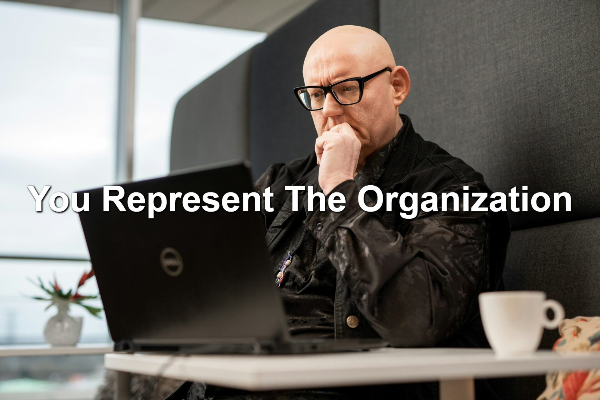 A bald man looking at a laptop screen