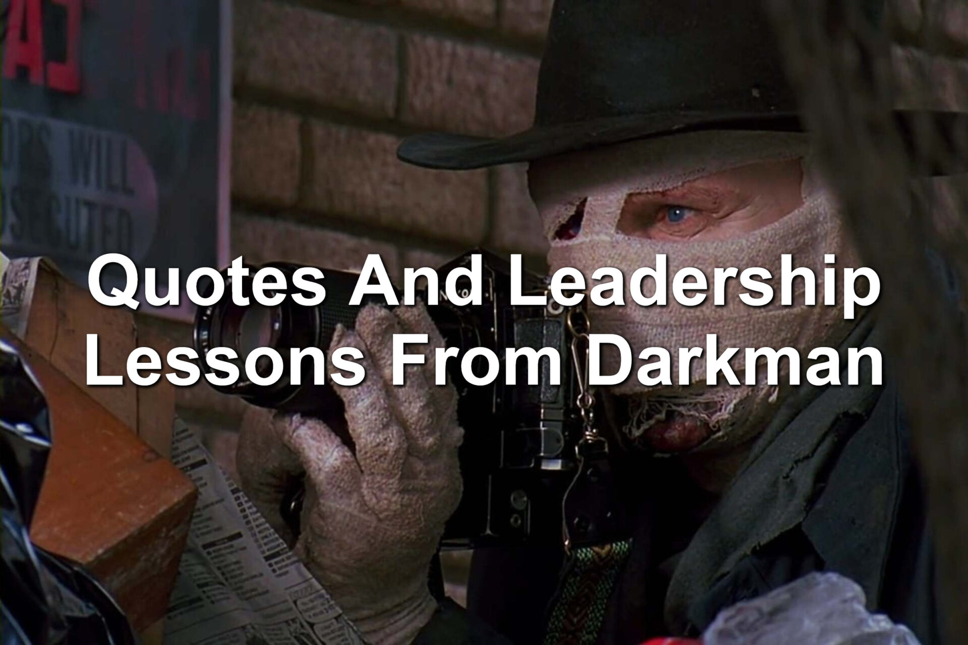Man with bandages on his face and hands. He's holding a camera in his hands. Scene from the movie Darkman. Starring Liam Neeson