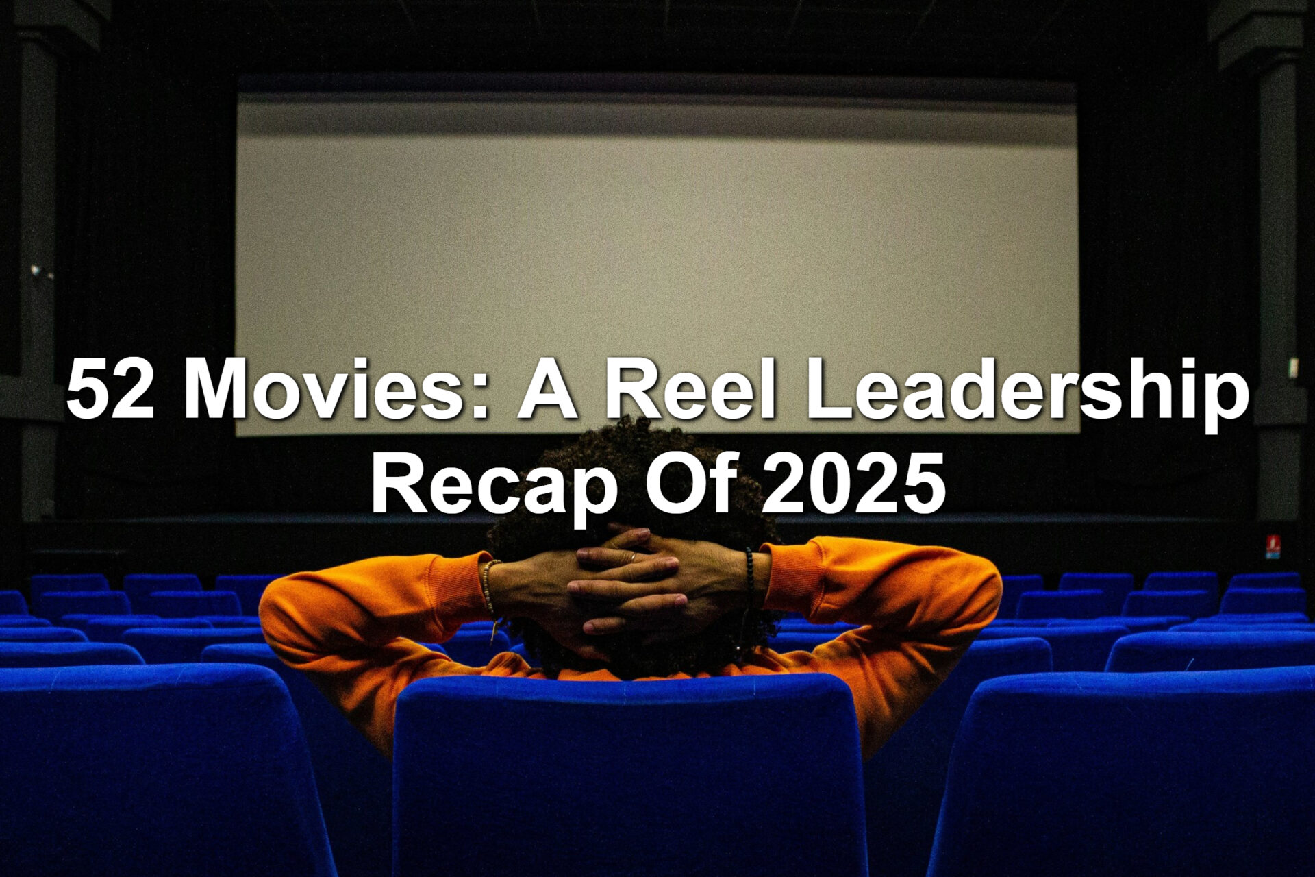 A man sitting in a blue theater seat. He's reclined, hands behind his head, and starring at a movie screen.