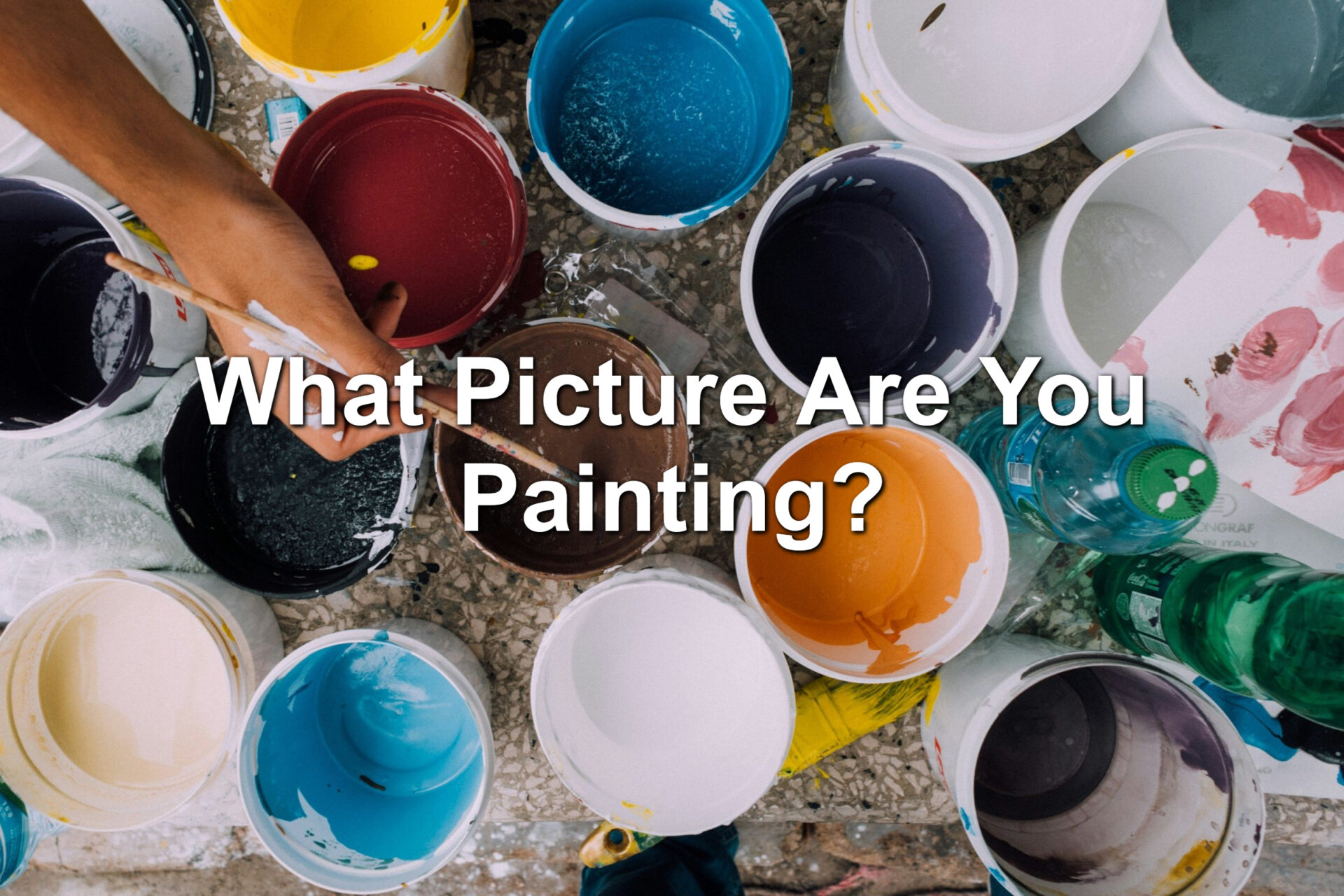 Paint cans on the floor. Various colors. A painter is dipping a brush into one of the containers.