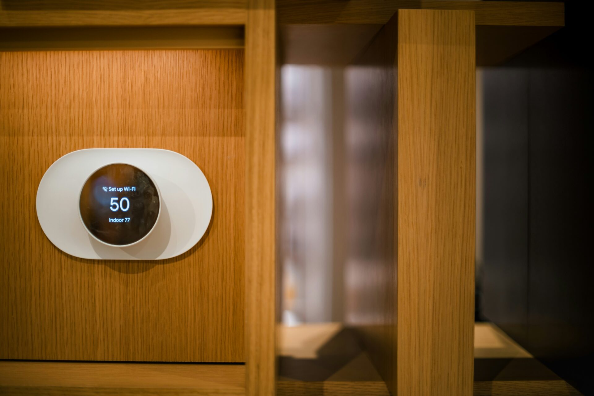 A smart thermostat handing on a wooden wall